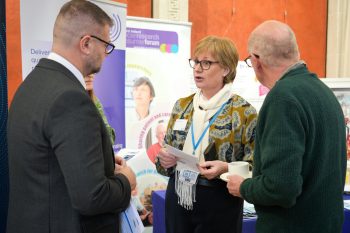 Melanie Morris Operational Director of NICTN and Colin Stephen McCormick, NICRCF member speaking to Colin McGrath MLA at Cancer Research UK Showcase event