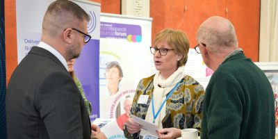 Melanie Morris Operational Director of NICTN and Colin Stephen McCormick, NICRCF member speaking to Colin McGrath MLA at Cancer Research UK Showcase event