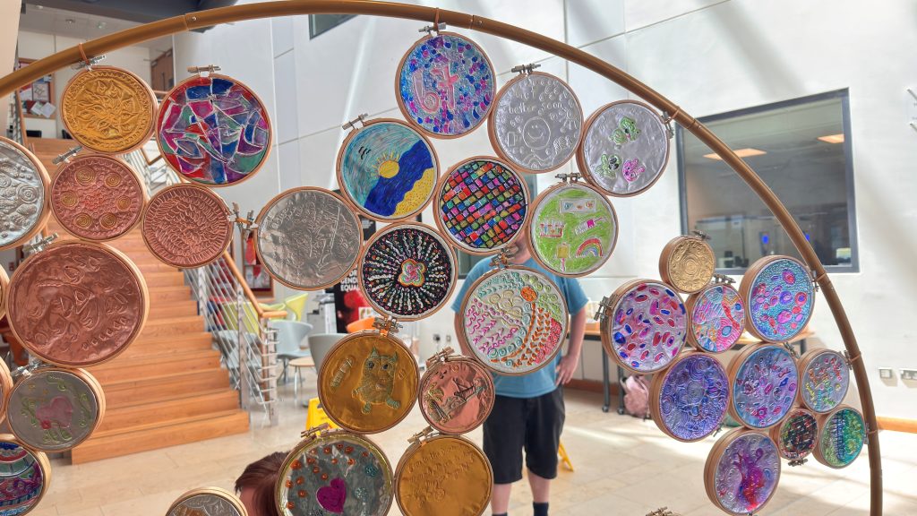 A wooden arch with a display of small round art pieces created on foil and coloured in